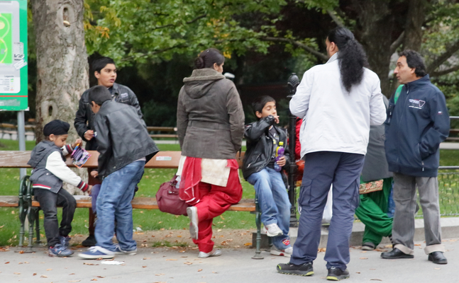 Ausländische Familie steht vor einer Sitzbank im Park 